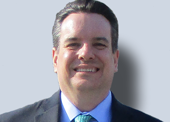Smiling man in suit with blue background.